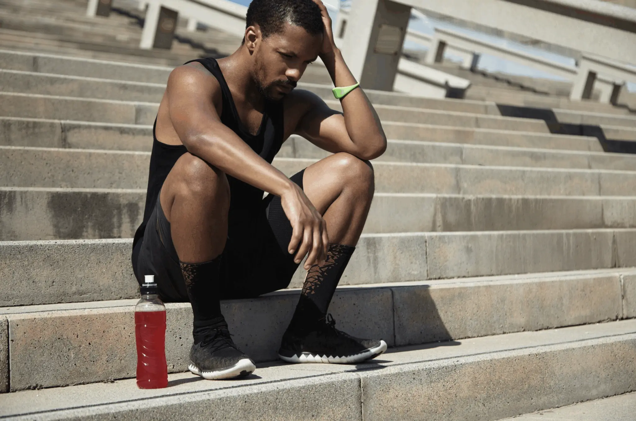 Man sitting on the stairs, thinking about whether pre-workout supplements could cause erectile dysfunction.