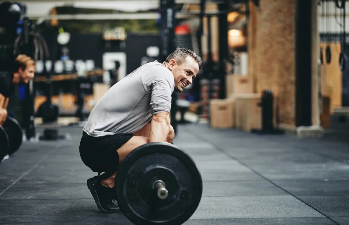 Man lifting a barbell at the gym, illustrating how Tirzepatide causes weight loss by supporting fat reduction, muscle preservation, and improved metabolic health.
