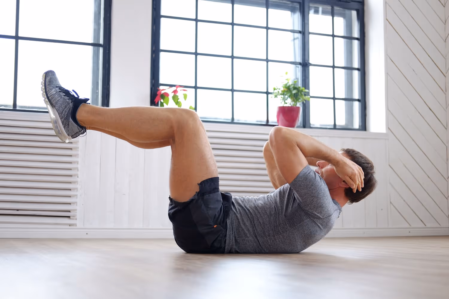 Man doing a bicycle crunch on the floor, focused and determined, highlighting pelvic floor exercises.