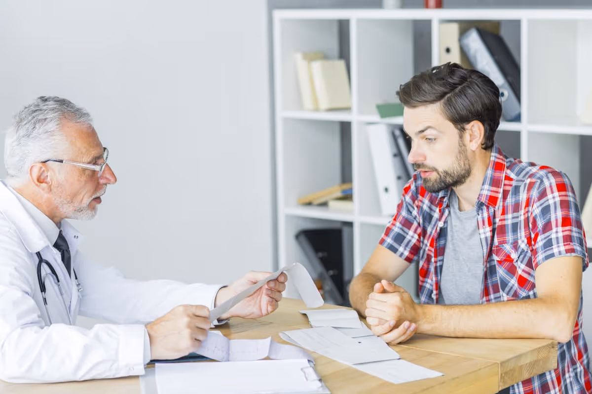 Doctor reviewing medical paperwork with a male patient during a consultation, illustrating a clinical discussion comparing P Shot vs GAINSWave.