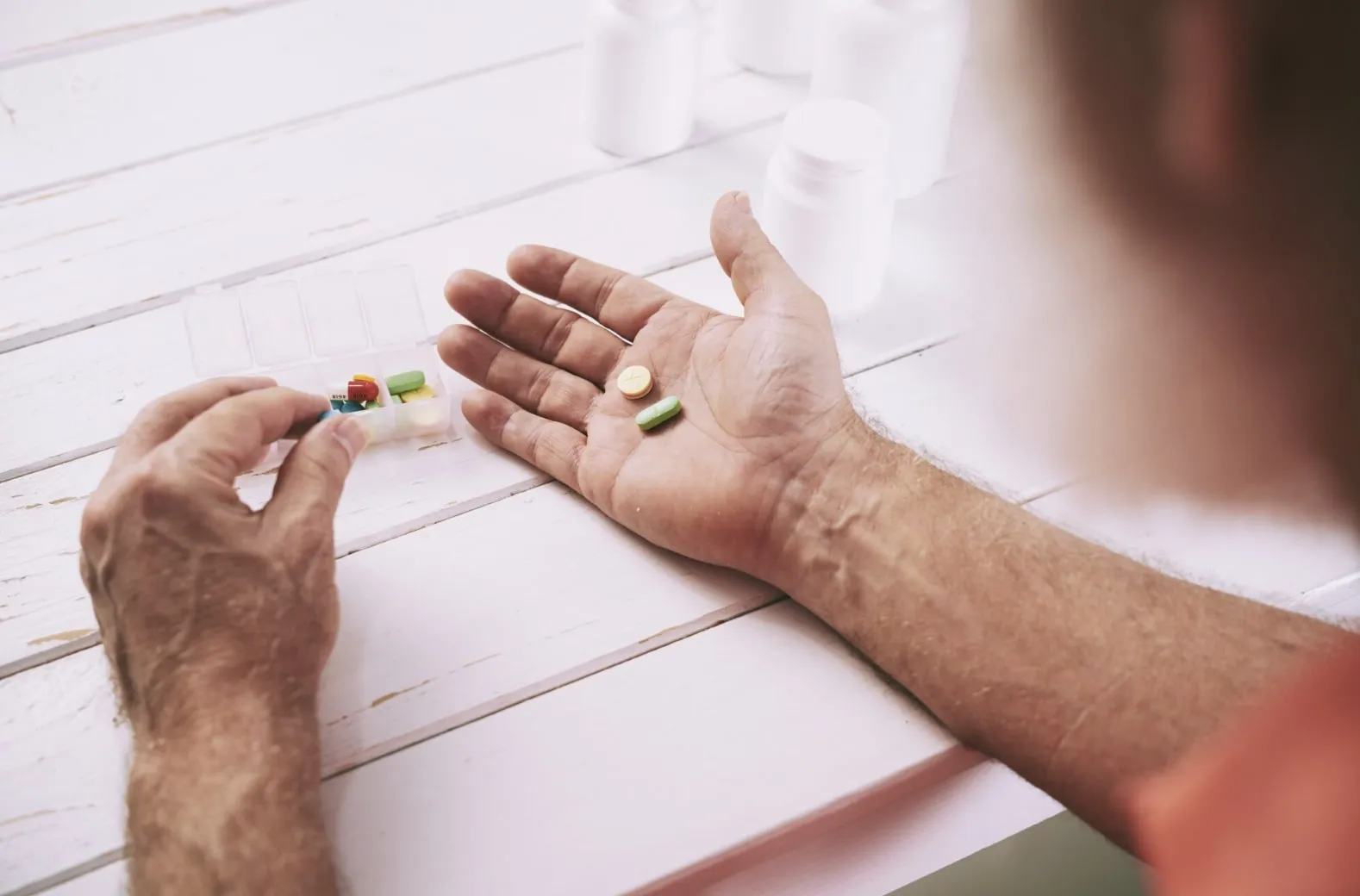 A close-up of a man’s hands holding pills, symbolizing the question of whether Cialis and Viagra can be safely taken together for erectile dysfunction treatment.