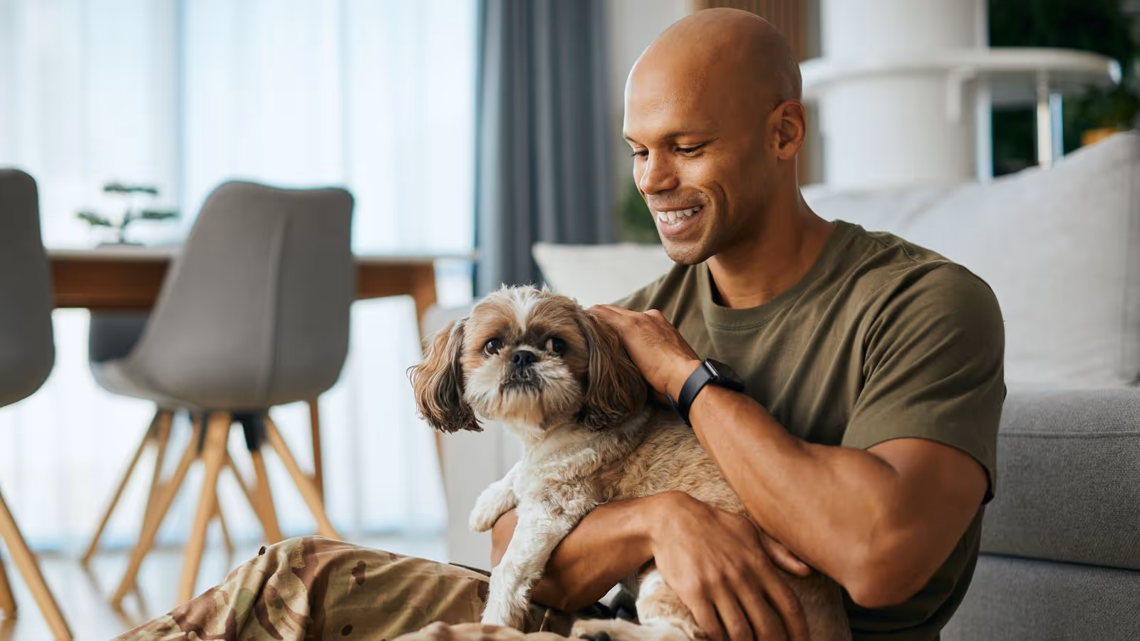 A military man smiles while petting his dog, reflecting the improved well-being and vitality that testosterone therapy offers to military members.