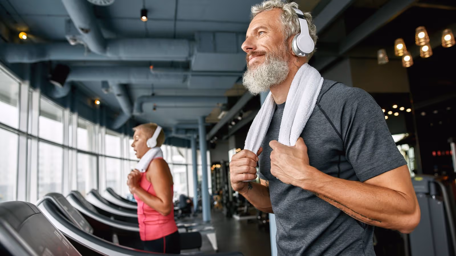 Older man and woman working out together on treadmills in a gym, representing the effectiveness of weight loss therapies for men.