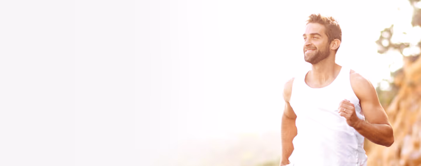 Smiling man jogging outdoors in sunlight, representing improved mood, motivation, and emotional well-being associated with testosterone therapy for depression.