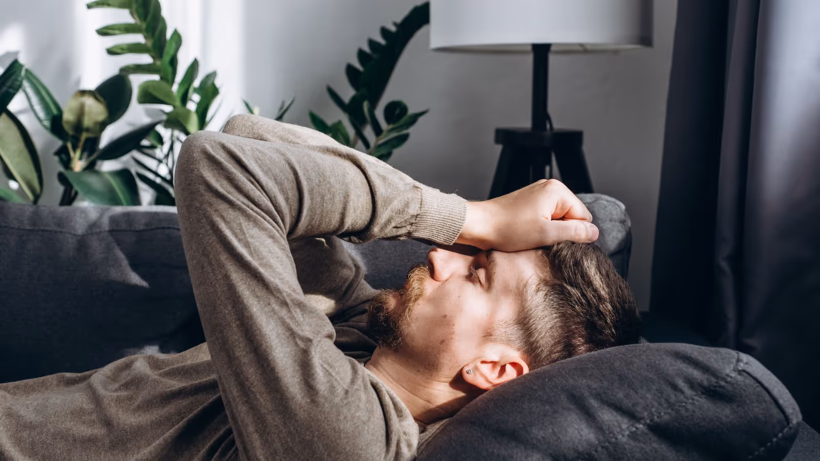 Man resting on couch, looking fatigued — low T symptoms suggested.
