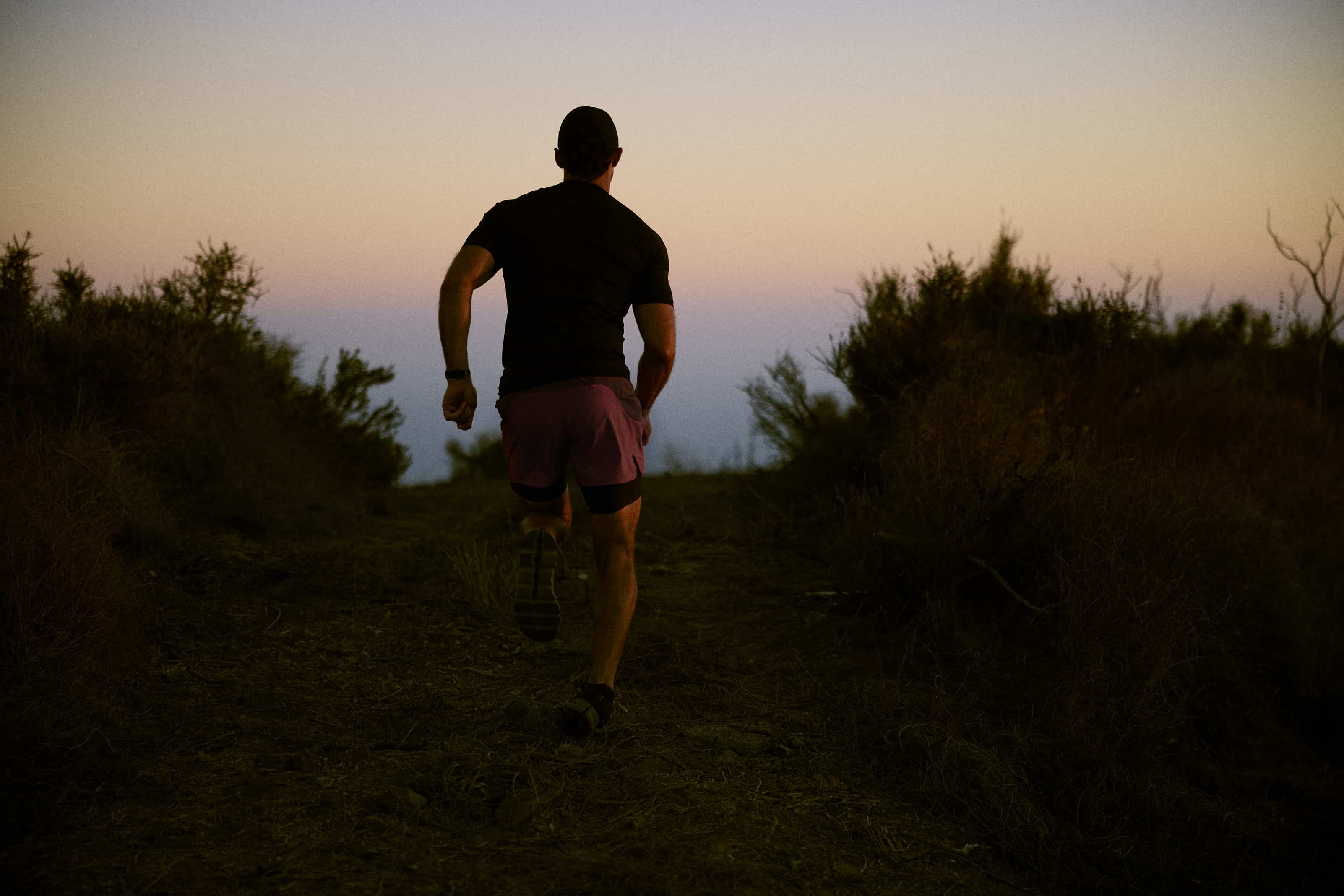 Man running on an outdoor trail at sunset, symbolizing improved energy, stamina, and physical performance explained in how TRT works in a beginner’s guide to testosterone replacement therapy.