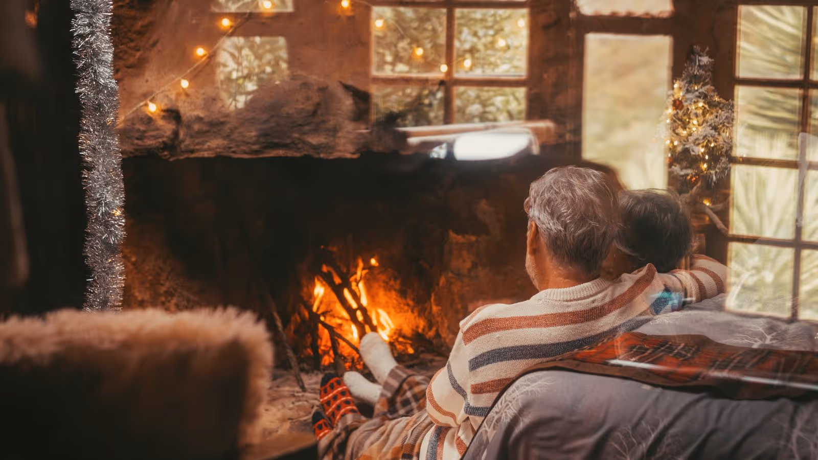 Couple embraces by a cozy fireplace with festive decorations.