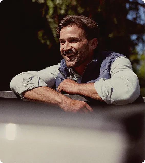 Confident man standing and smiling outdoors, representing improved wellness and vitality associated with the P-Shot treatment.