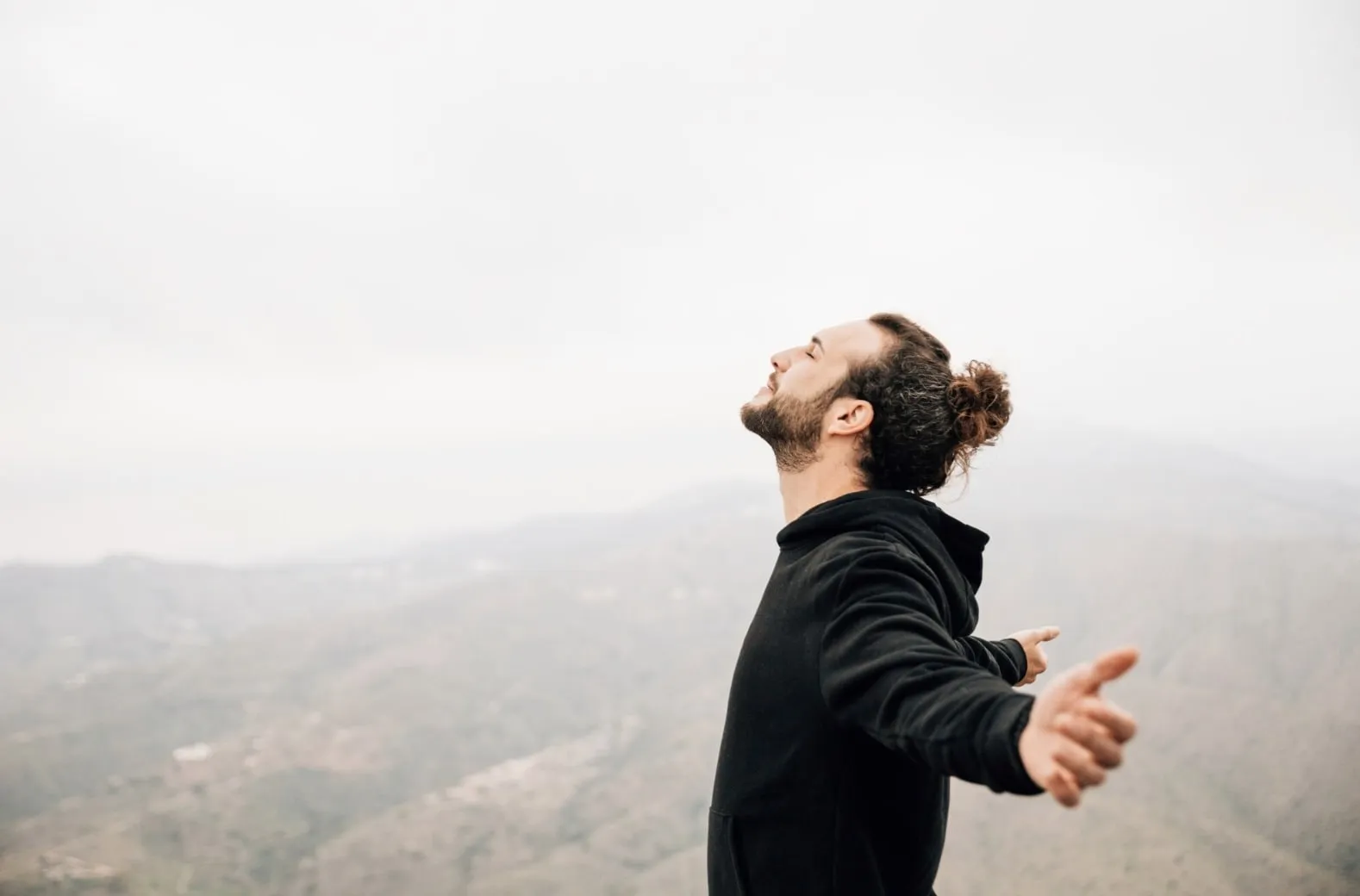 A man happily standing on a mountain peak, symbolizing renewed confidence and a fresh start thanks to effective ED treatment options for 2026.