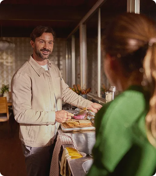 Smiling man engaging with a woman while preparing breakfast, symbolizing renewed energy, vitality, and improved quality of life achievable through Oral TRT and Kyzatrex therapy.