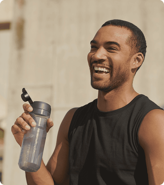 Man smiling and holding a water bottle after exercise while using Semaglutide for weight loss, appetite control, and metabolic support.