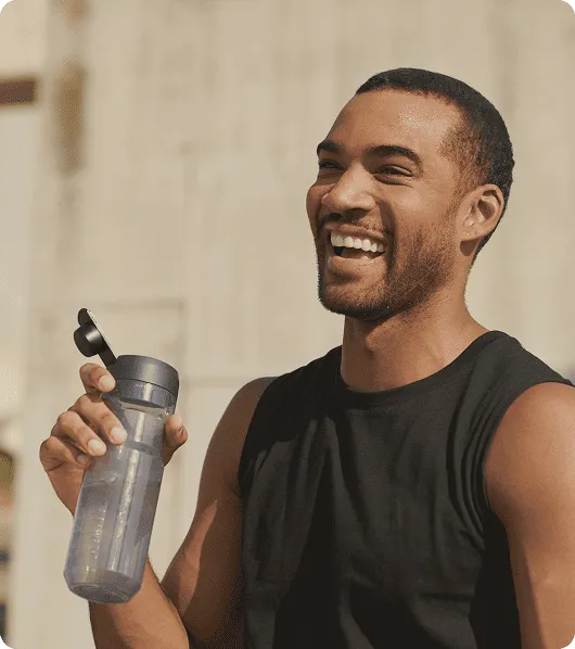 Man smiling and holding a water bottle after exercise while using Semaglutide for weight loss, appetite control, and metabolic support.