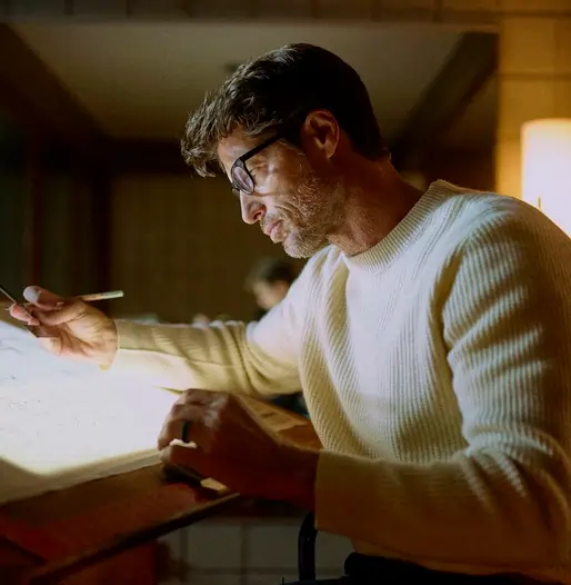 Man wearing glasses reading in a warm indoor setting, representing long-term hair preservation and DHT reduction supported by Finasteride treatment.
