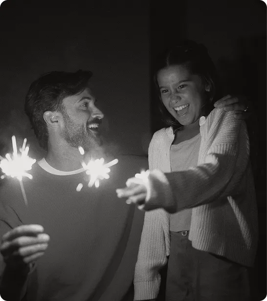 Man celebrating with his daughter while holding sparklers, representing enhanced daily energy and mood supported by Vitamin B12 injections.