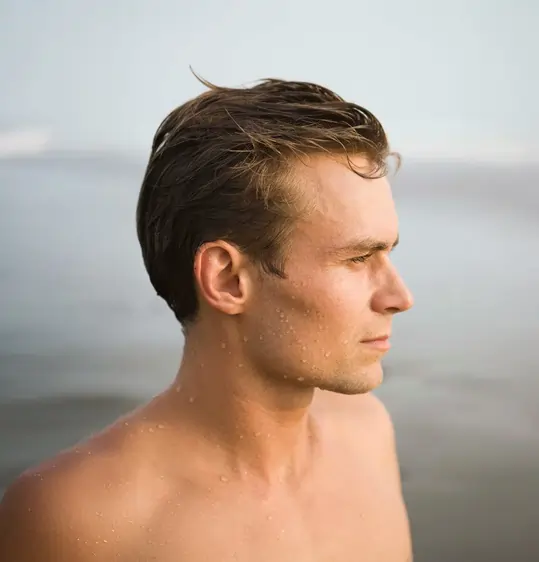 Man standing near the ocean with styled hair, illustrating natural hair restoration and density improvements from PRP for Hair Loss treatment.