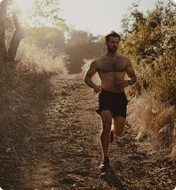 Man running on a forest trail, representing enhanced energy, endurance, and workout performance supported by Tri-Amino acid injections.