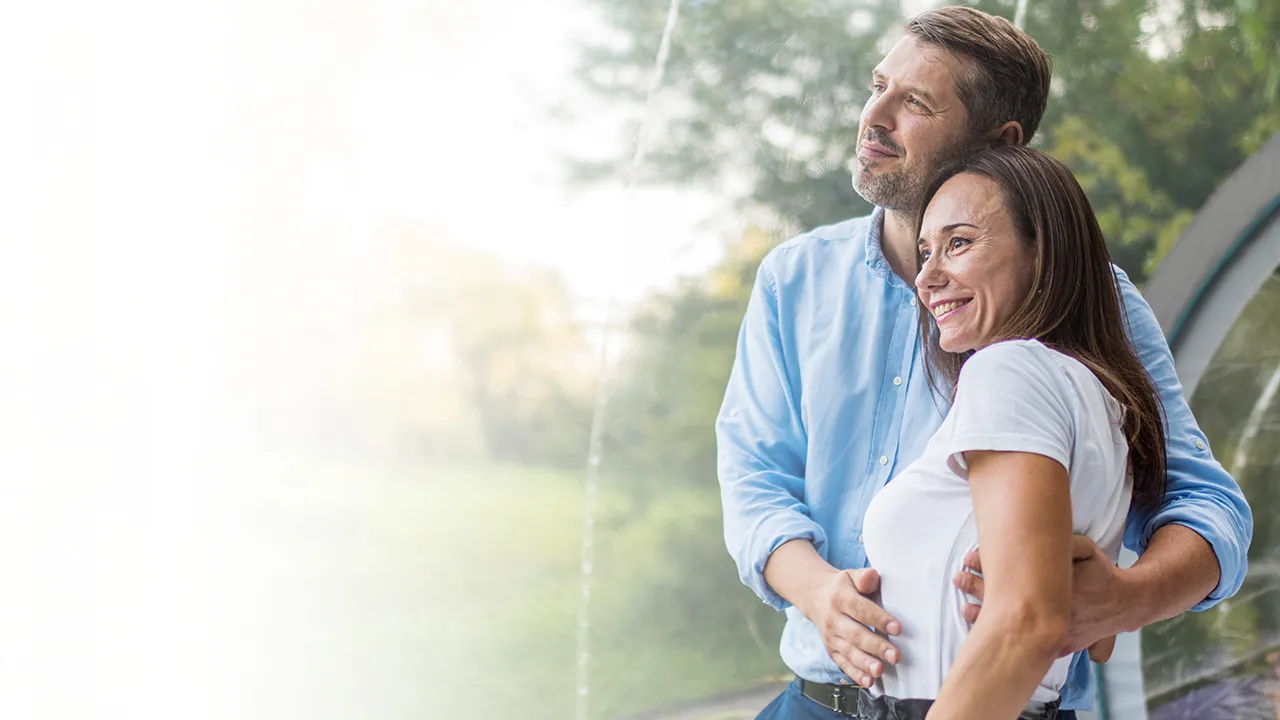 Healthy couple standing together and smiling, representing improved wellness, vitality, and overall health benefits associated with glutathione injections.