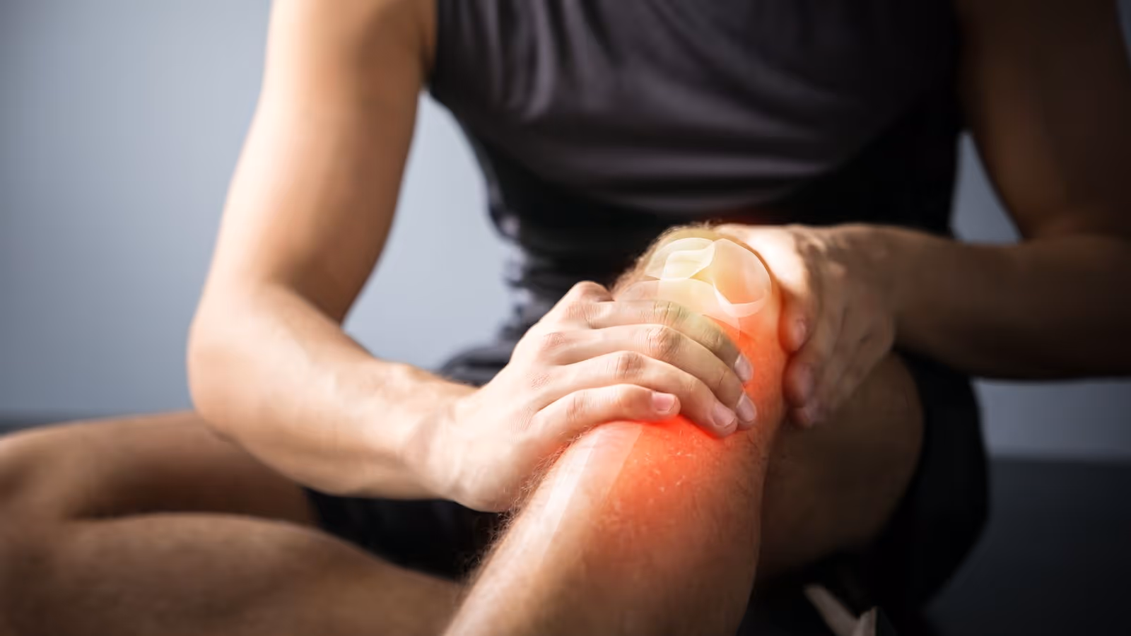 Person holding knee in pain, with red highlight, symbolizing injury—shockwave therapy may help.