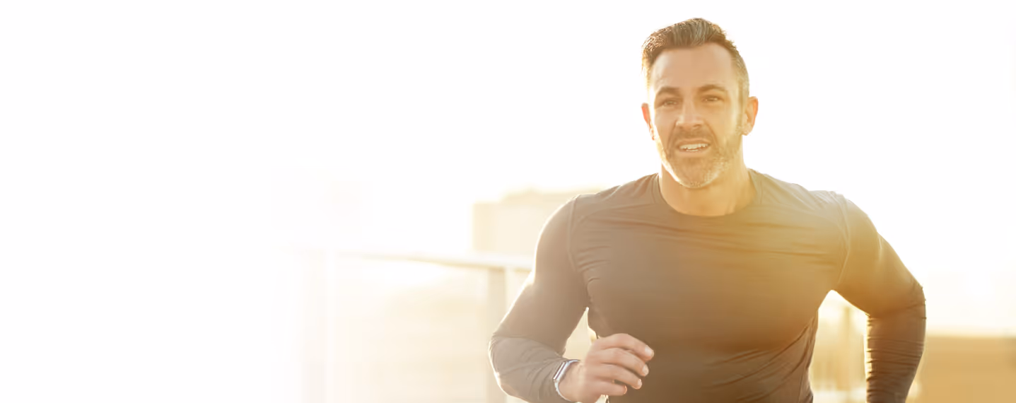 Fit adult man running outdoors in sunlight, representing increased energy, motivation, and results associated with men’s weight loss with phentermine.