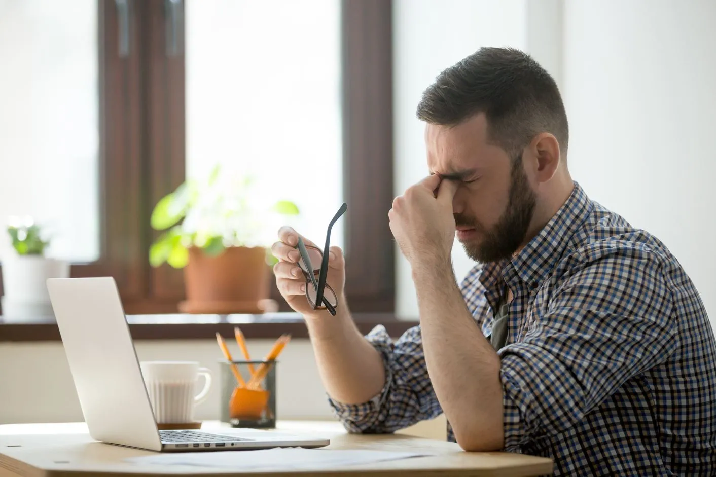 A man rubbing his eyes in frustration, reflecting the fatigue and discomfort often associated with low testosterone, a condition that can impact mood, energy, and overall well-being.