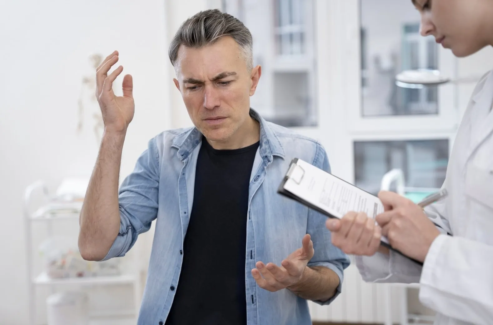 A man expressing frustration during a medical consultation, reflecting the struggles some individuals face with erectile dysfunction.