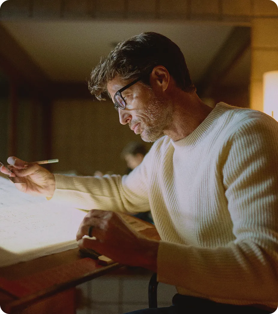 Man wearing glasses reading in a warm indoor setting, representing long-term hair preservation and DHT reduction supported by Finasteride treatment. 