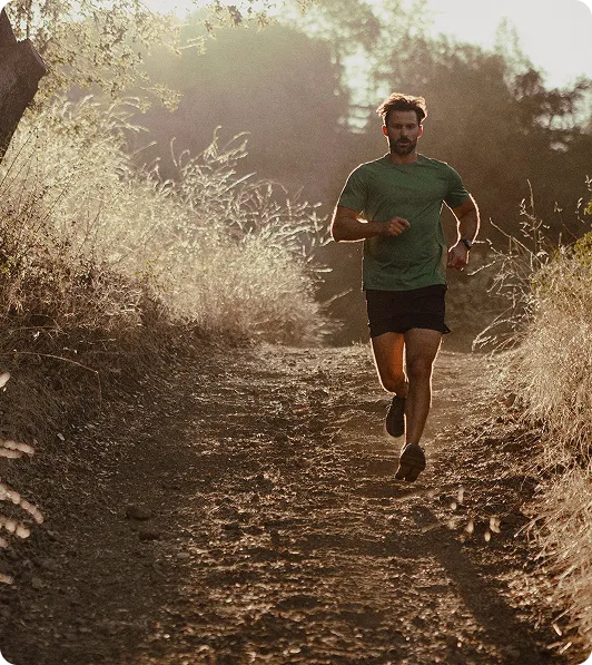 Fit man running along a scenic path during sunrise, representing the energy, vitality, and improved well-being that can result from Clomid or Enclomiphene therapy.