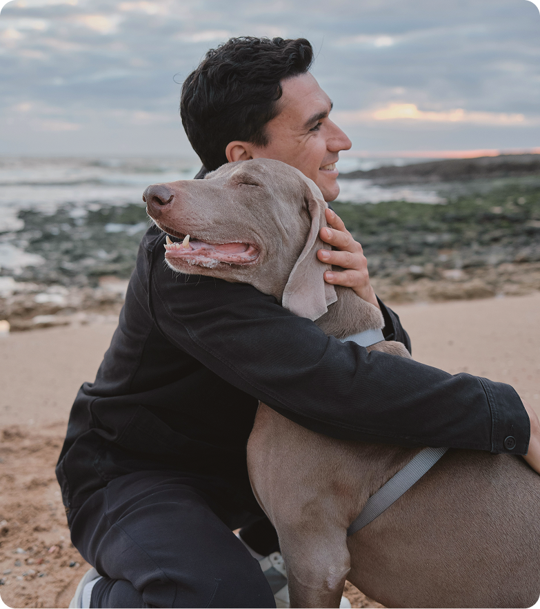 Smiling man on the beach with a dog, reflecting quality-of-life improvements associated with testosterone pellet treatment in Burlington, NC.