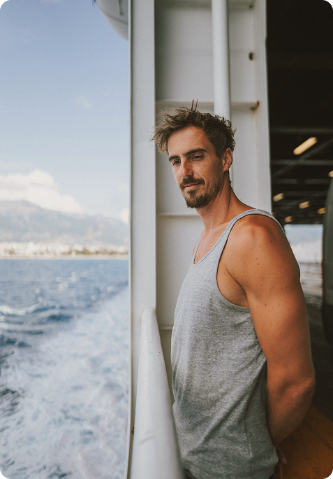 Confident man standing on a ship overlooking the ocean, symbolizing focus, motivation, and well-being associated with Testosterone Cypionate Injections in Burlington, ON.