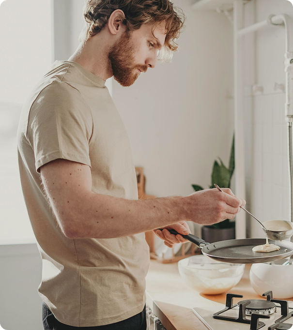 Fit man cooking pancakes in a home kitchen, symbolizing everyday nutrition awareness and lifestyle balance associated with GLP-1 Medications in Markham, ON.