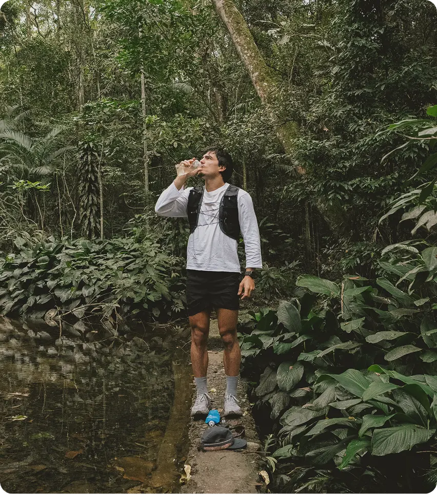 Fit man drinking water in a forest setting, symbolizing vitality, recovery, and lifestyle support associated with GHRH Injections in Aurora, ON.