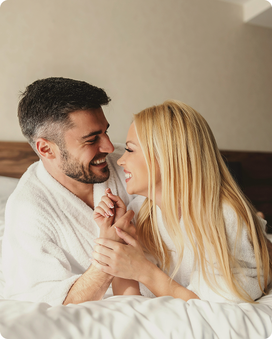 Couple smiling together in bed, representing improved intimacy and comfort associated with Shockwave Therapy for Erectile Dysfunction in West Edmonton, AB.