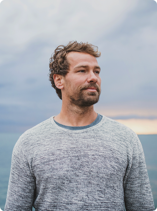 Smiling man near the ocean, symbolizing lifestyle confidence and hair preservation supported by Finasteride therapy in Burlington, NC.
