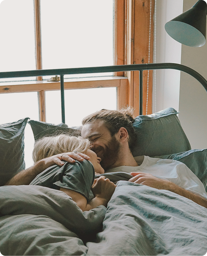 Smiling couple lying in bed in Burlington, NC, symbolizing renewed intimacy and sexual confidence supported by ED treatment at Gameday Men’s Health.