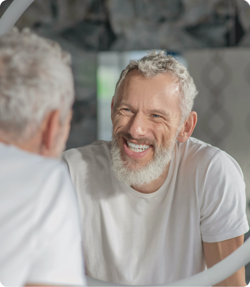 An older man looking in the mirror, reflecting subtle facial refinement after Dysport injections at Gameday Men’s Health in Syracuse, NY