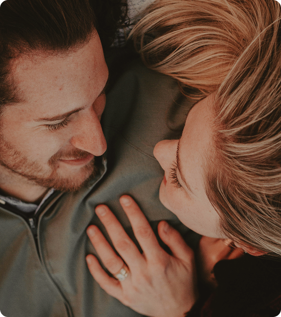 Man and woman lying in bed smiling together, reflecting relationship confidence supported by Shockwave Therapy for ED in Des Moines