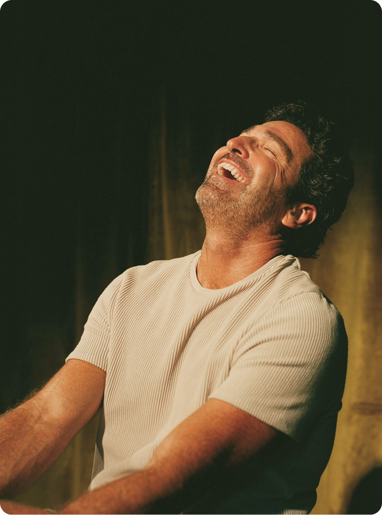 Man sitting and smiling in a relaxed setting, reflecting improved mood and well-being supported by Oral TRT Kyzatrex in Des Moines