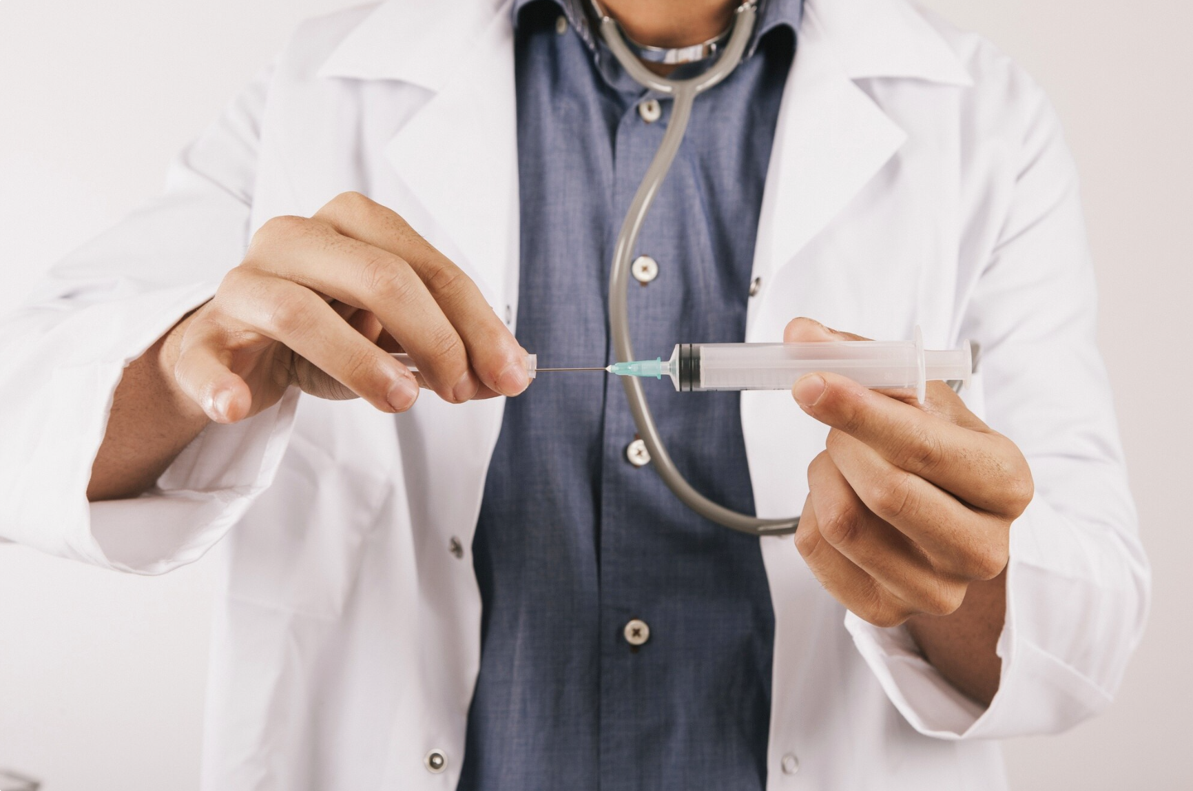 Doctor holding a syringe during medical consultation, representing clinical administration and explanation of how semaglutide treatment works