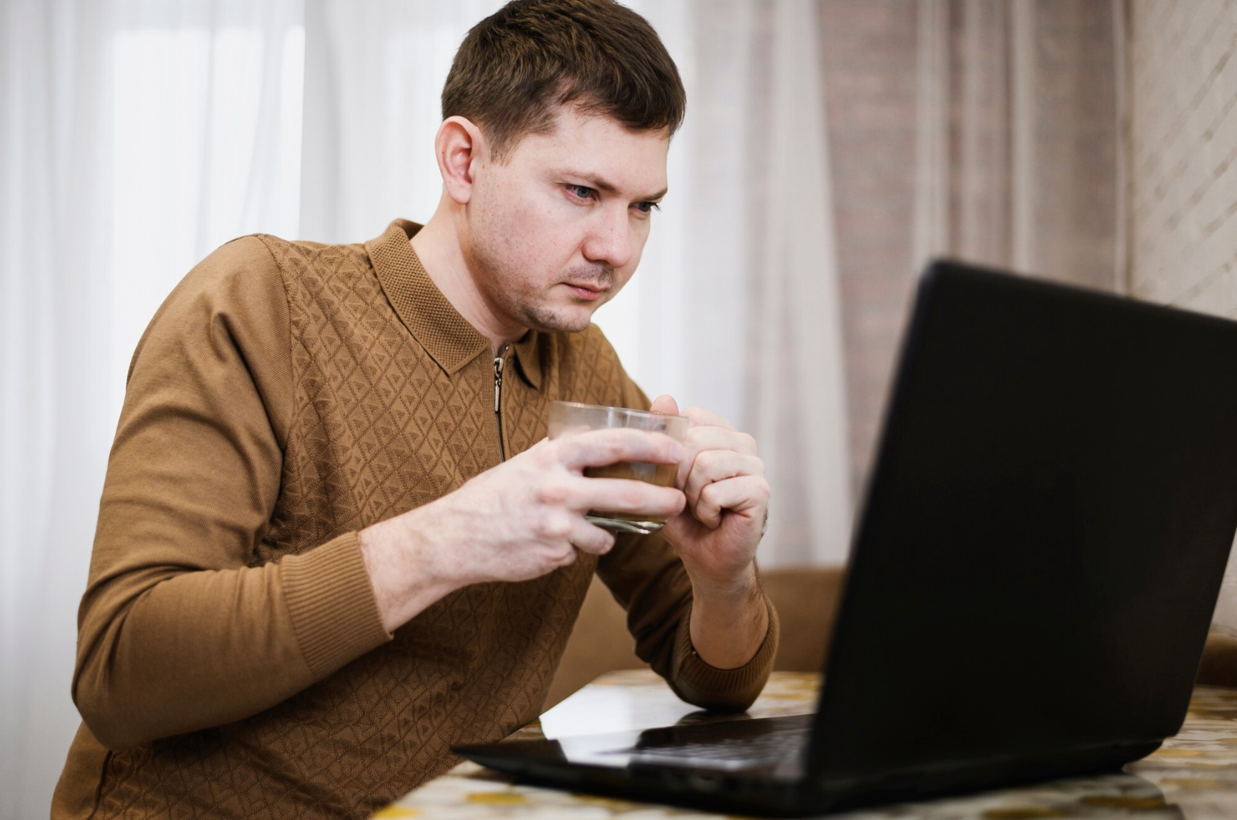 Man reading information on a laptop at home, researching how long phentermine stays in the body and its duration of effects