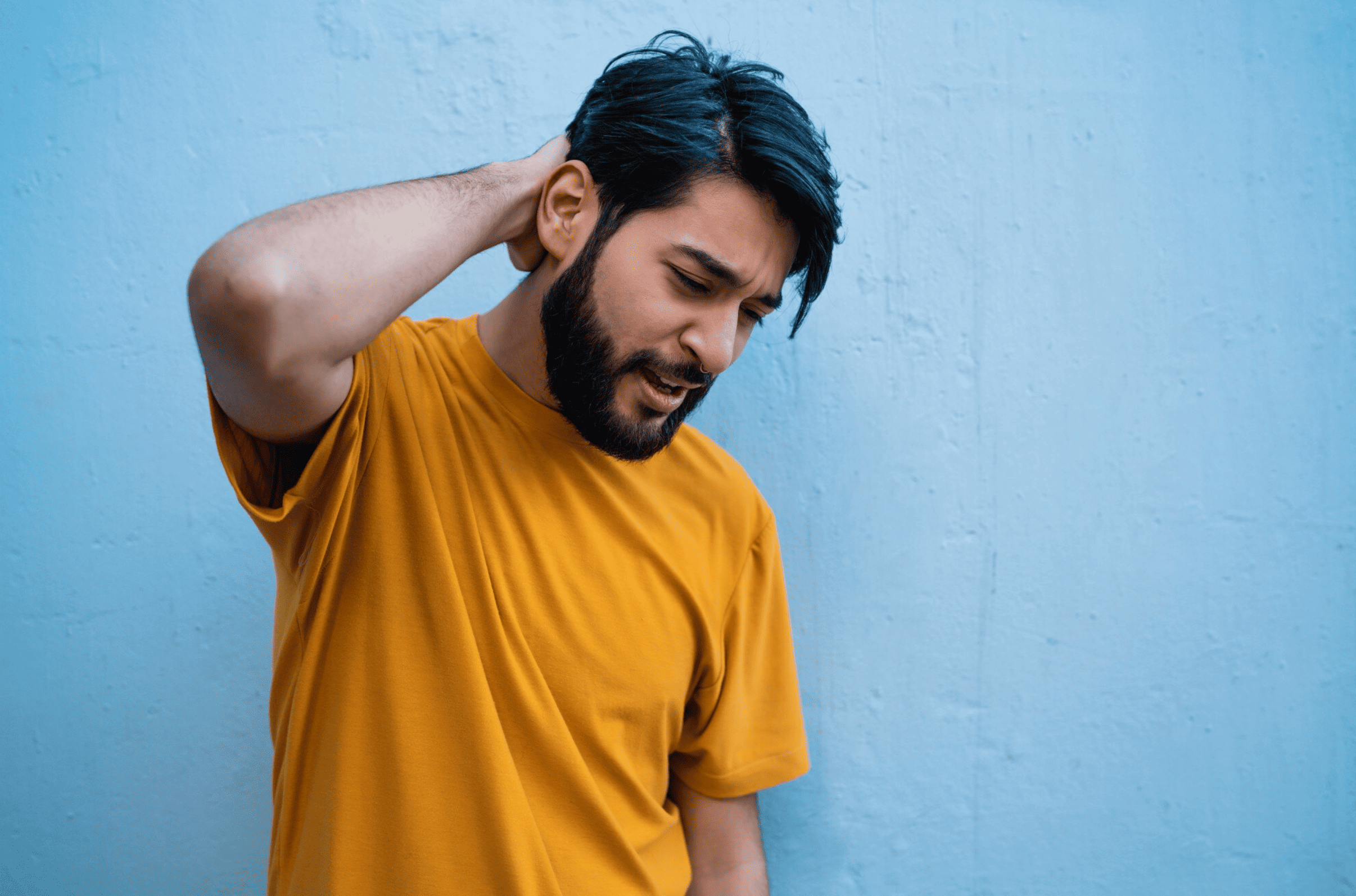 Man standing near a wall in a thoughtful pose, representing awareness and considerations around finasteride side effects