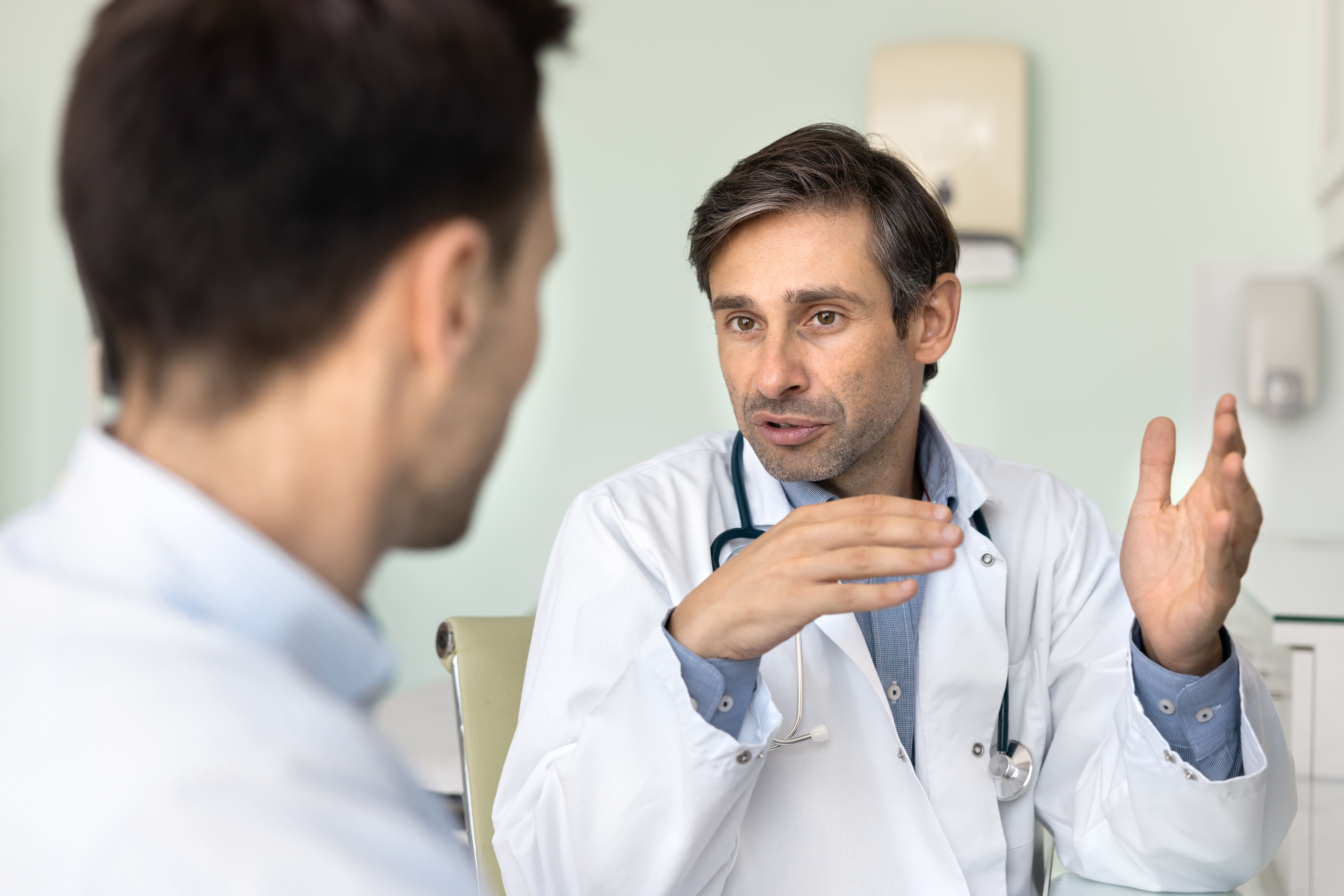 Doctor discussing treatment options with male patient in clinic