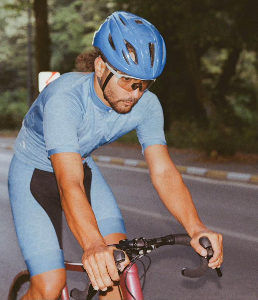 Man riding a bicycle on an open road, representing endurance, focus, and vitality supported by NAD+ injection therapy in San Mateo County, CA.