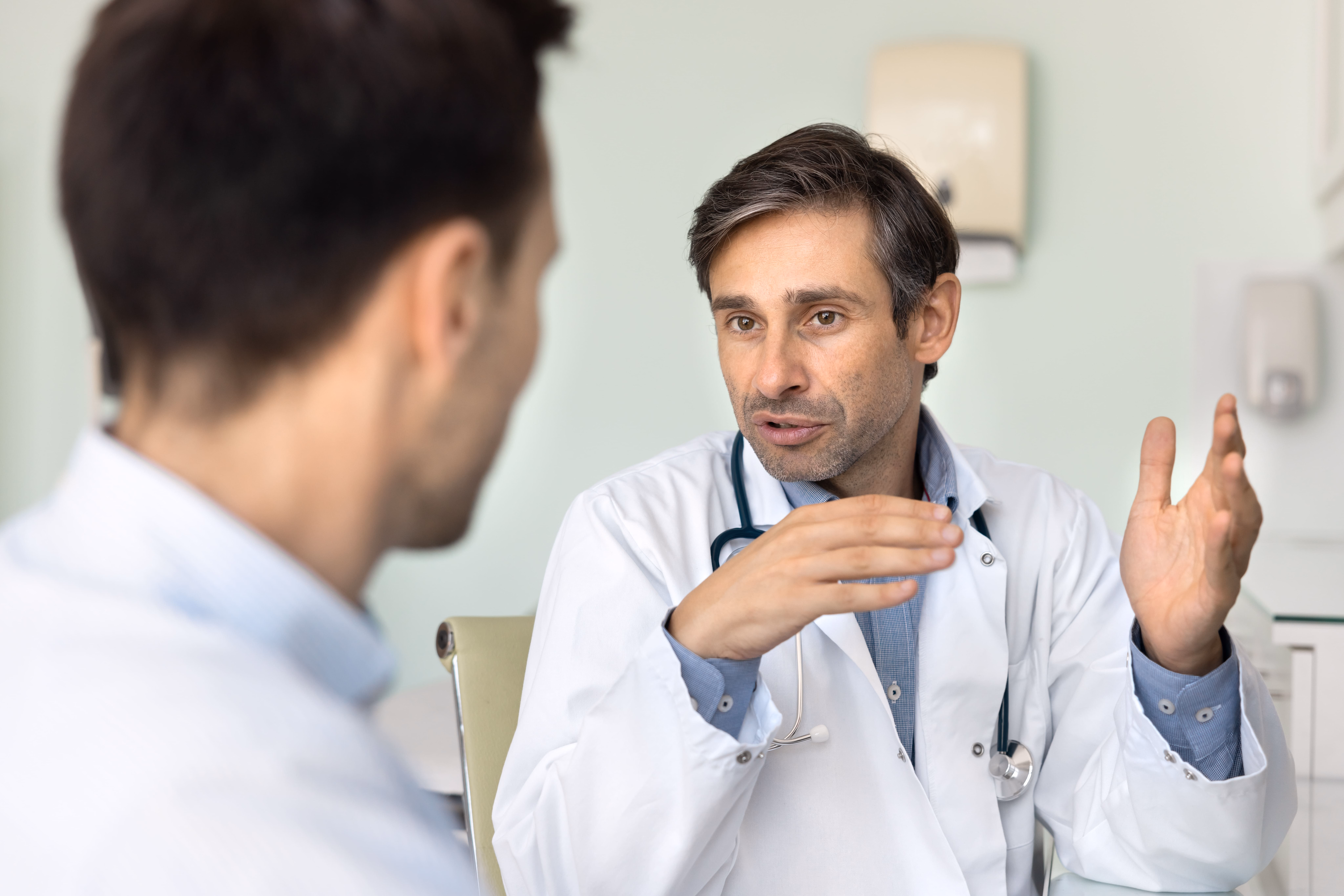 Doctor discussing treatment options with male patient in clinic
