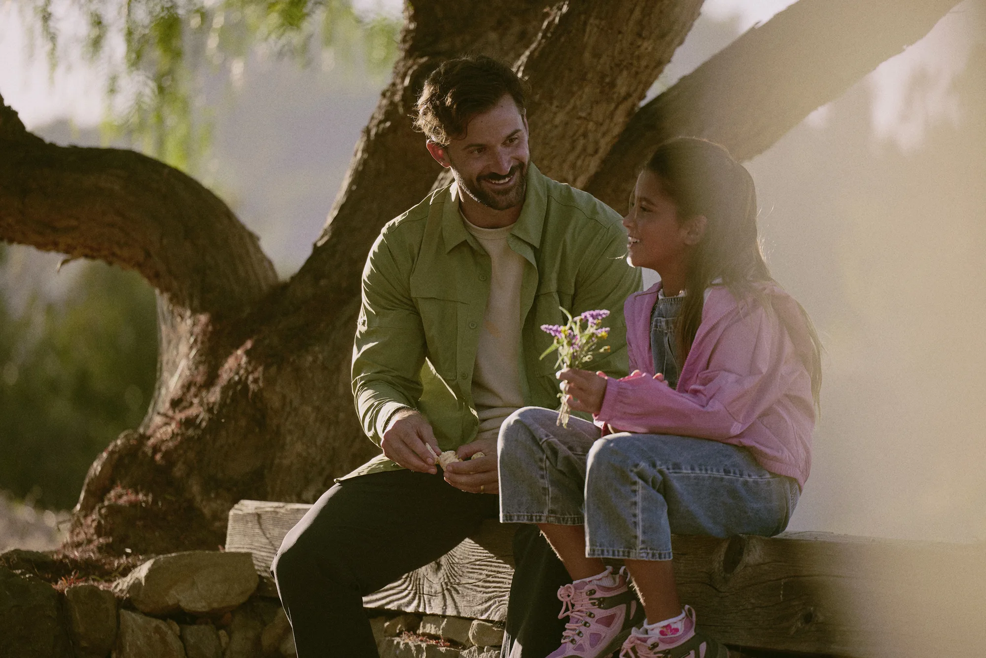 Smiling couple sitting together under a tree outdoors