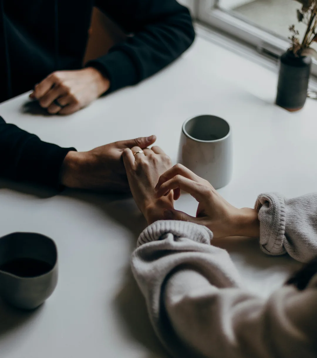 Two people holding hands across a table.