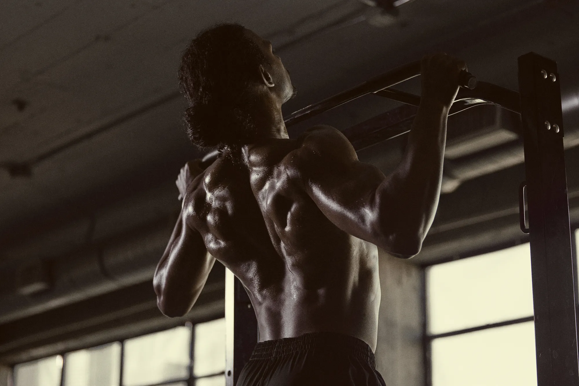 Man doing pull-ups in a dim warehouse gym