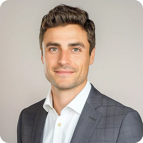 Smiling man with short dark hair wearing a dark checkered suit jacket and white shirt against a light background.