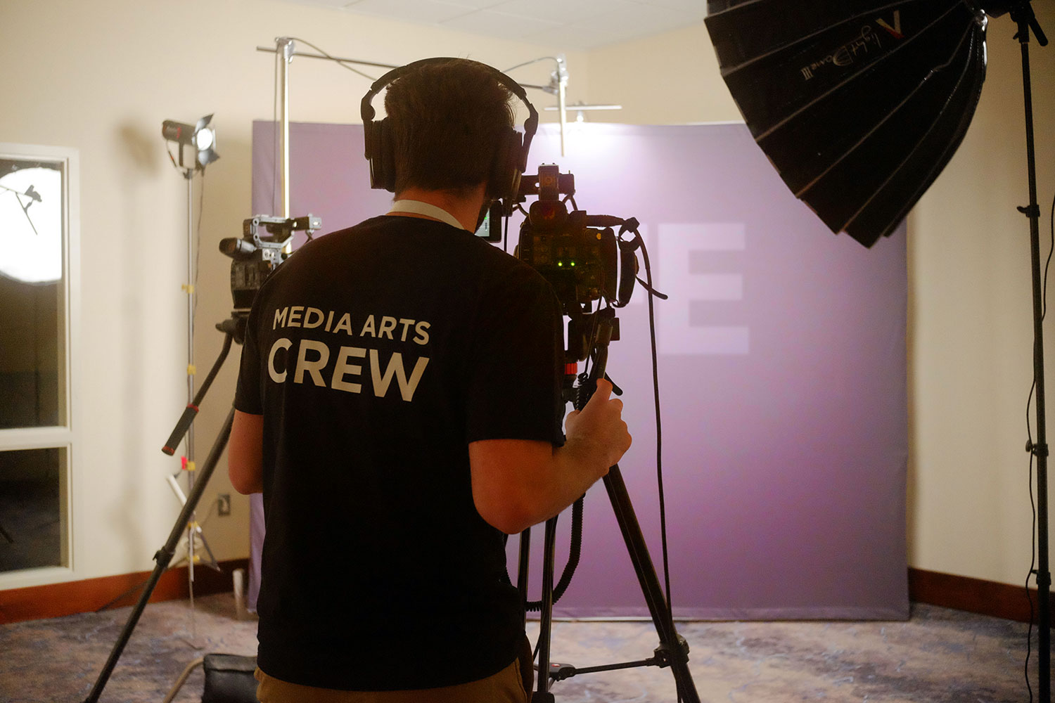 Media Arts crew member behind camera in staged testimonial set