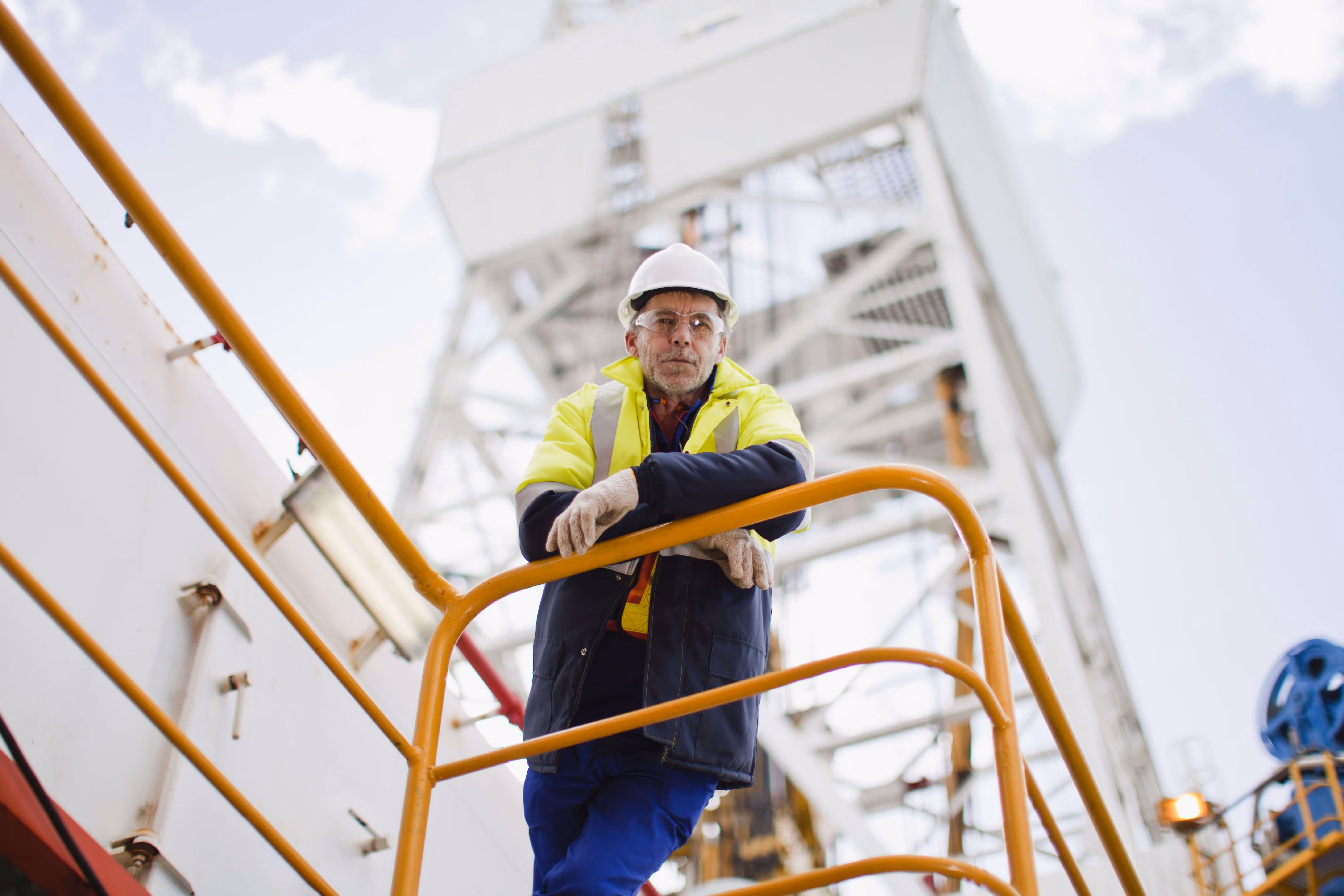 Man on an oil rig looking down at camera
