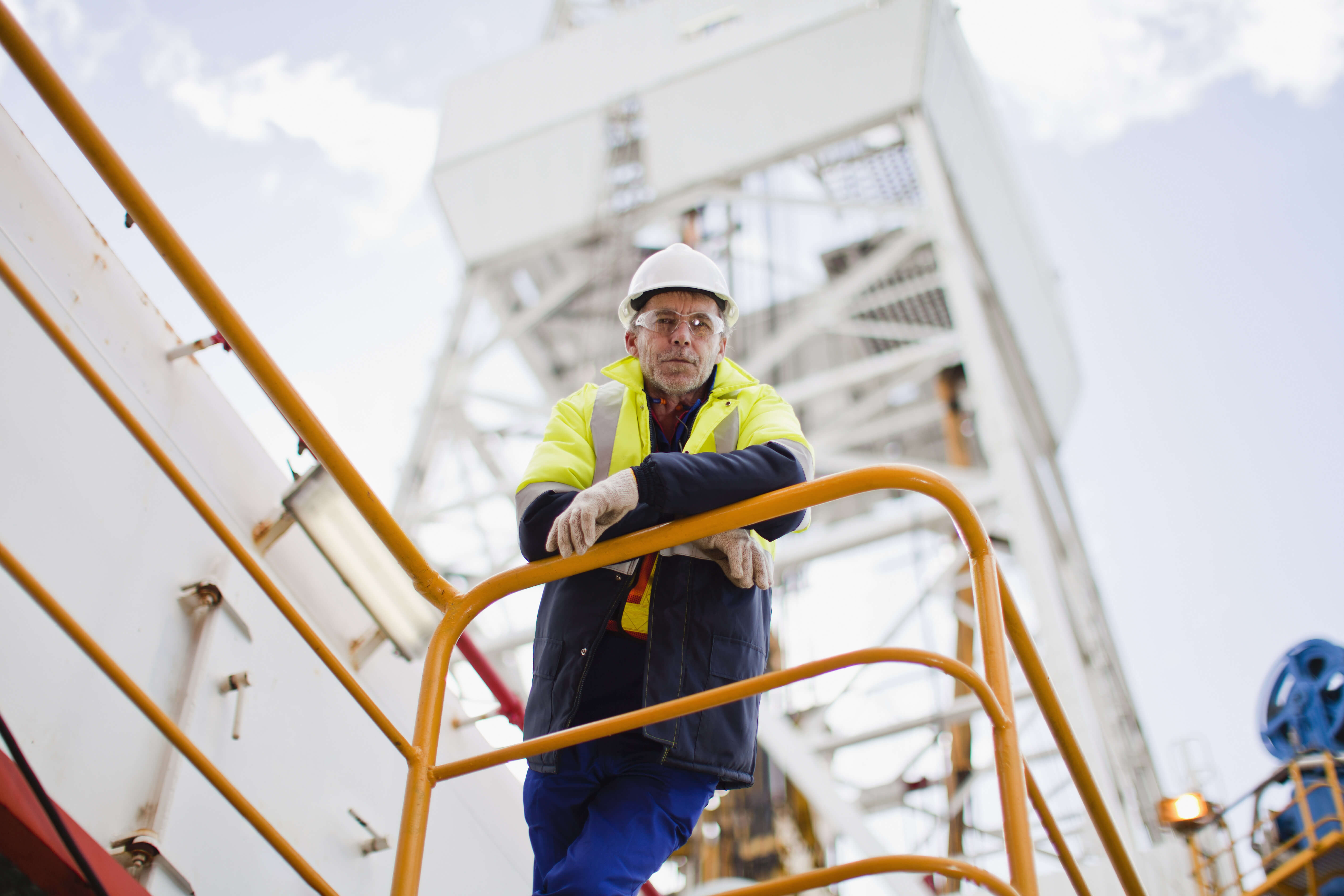 Man on an oil rig looking down at camera